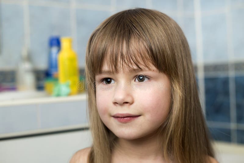 Pretty girl face portrait, smiling child with beautiful eyes and long wet fair hair on blurred background of bathroom stock photography Pretty girl face portrait, smiling child with beautiful eyes and long wet fair hair on blurred background of bathroom stock photography
