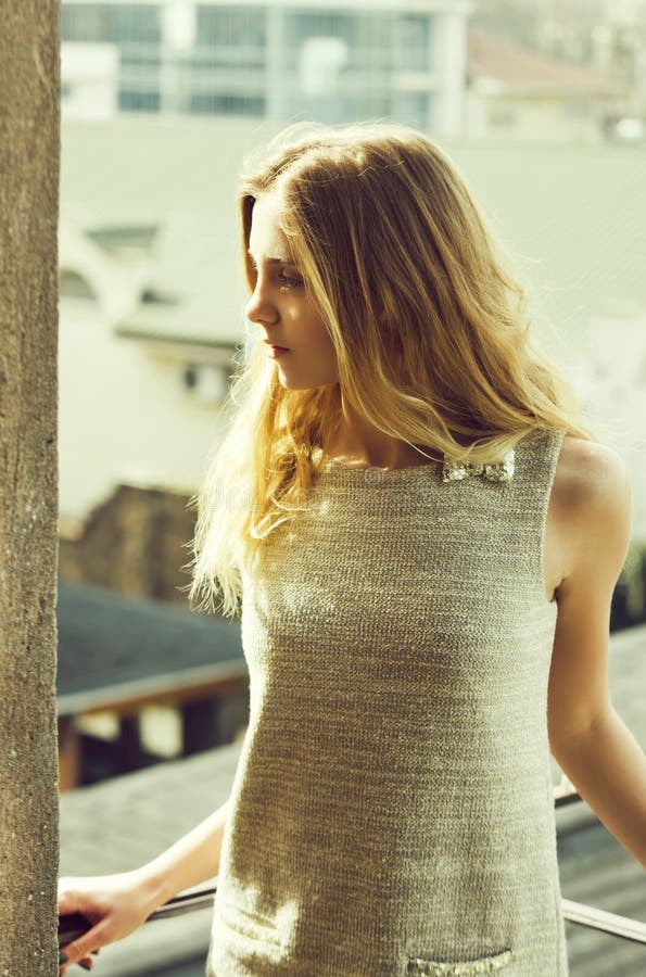 Pretty girl in fashionable grey dress on balcony