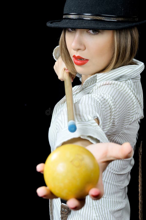 Pretty girl in hat with billiard cue and a ball