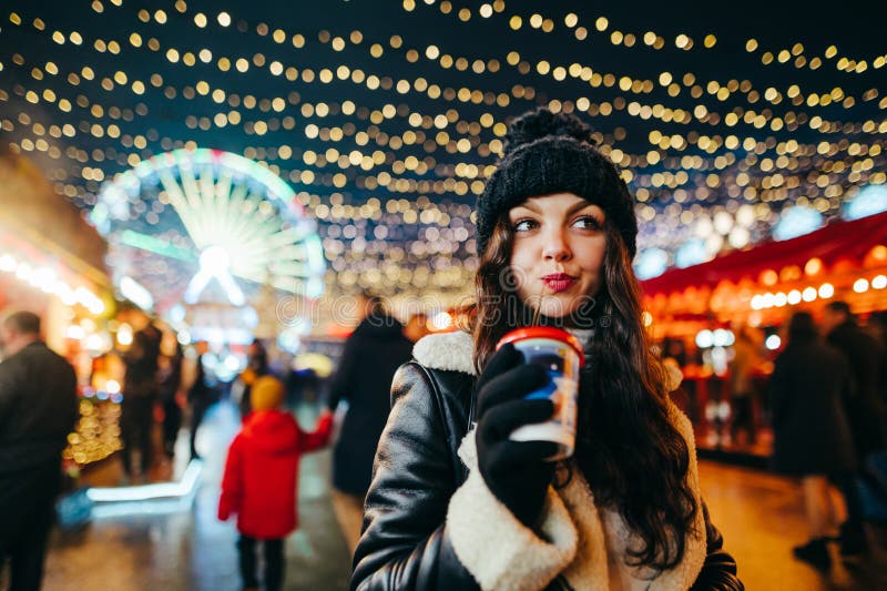 A Pretty Girl in a Hat and Winter Clothes Walks Down the Christmas ...