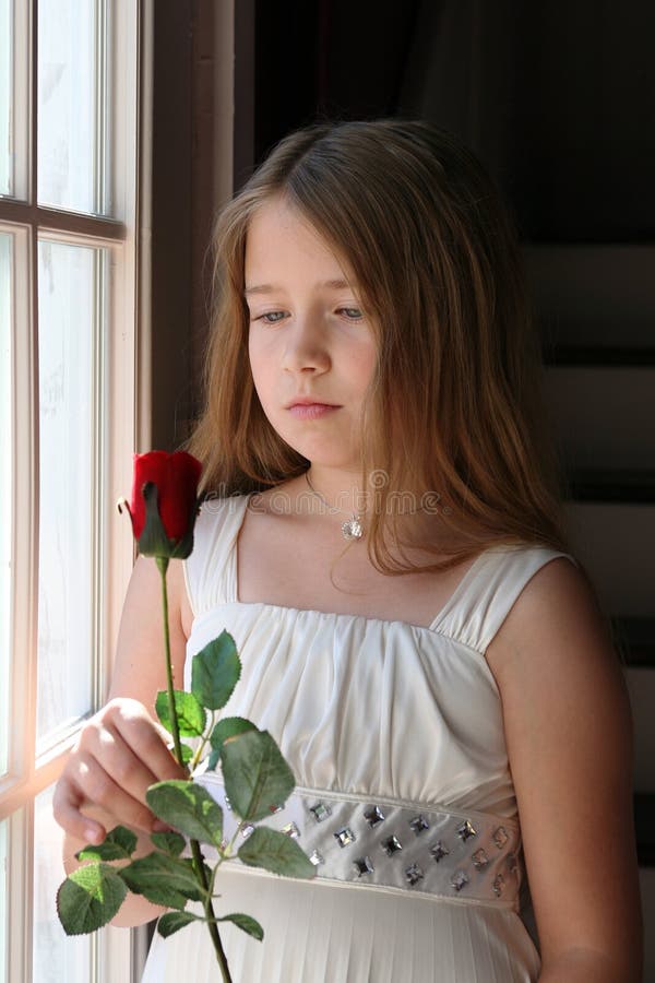 Pretty girl holding a red rose next to window