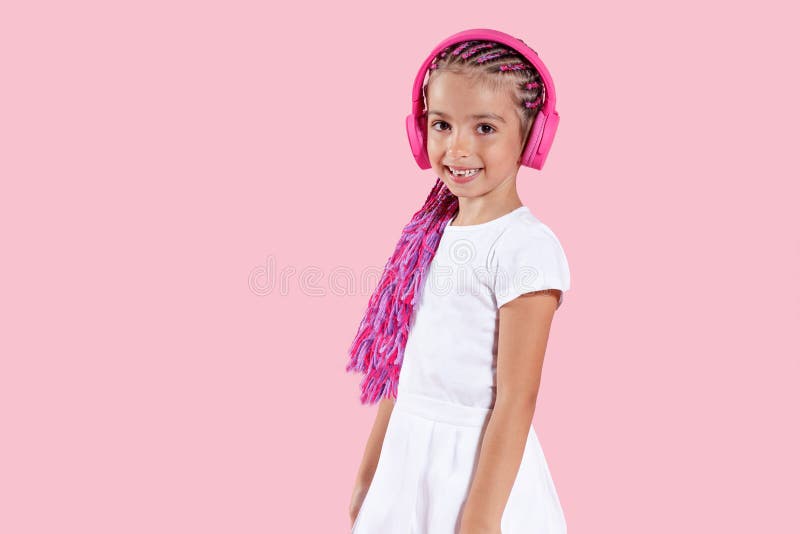 Pretty Girl Listening Music In Pink Headphones On Pink Background. Studio Portrait. Copy space.