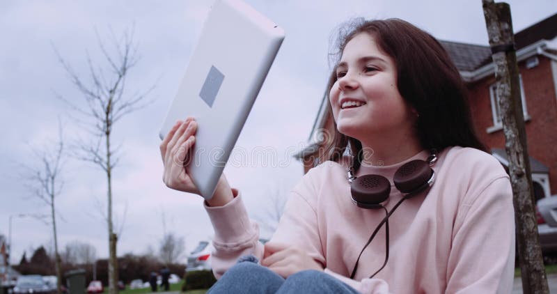Pretty girl in pink vest with tablet computer in front of country street. Young girl using tablet computer and smiling stock video footage