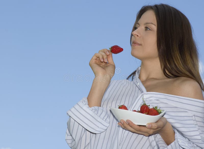 Pretty girl relaxing on balcony and eat red fresh