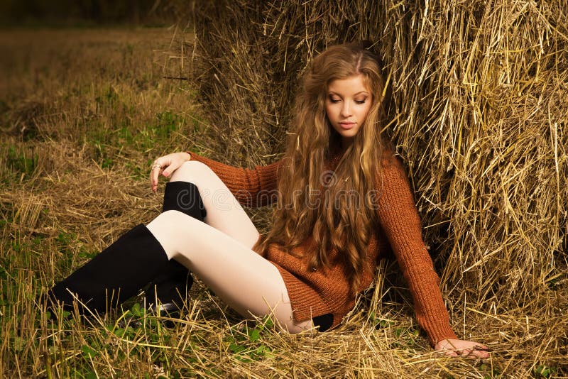 Pretty girl resting on straw bale