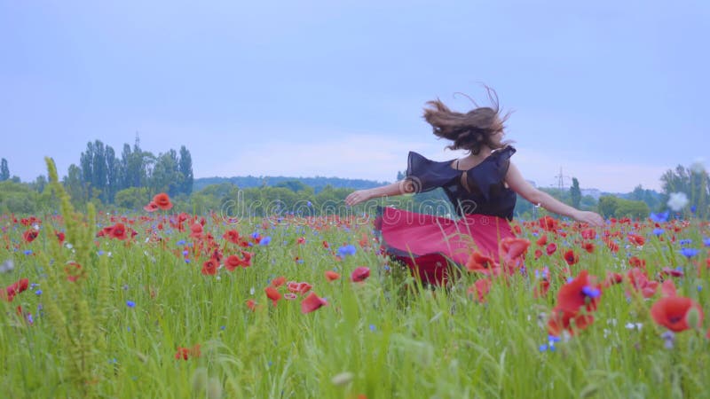 Pretty girl running and dancing in a poppy field smiling happily. Connection with nature. Leisure in nature. Blossoming