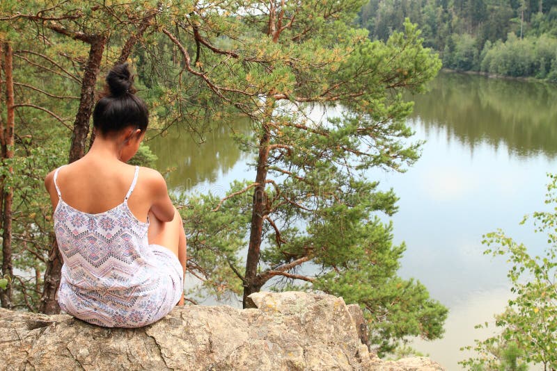 Pretty girl sitting on rock watching water royalty free stock images Pretty girl sitting on rock watching water royalty free stock images