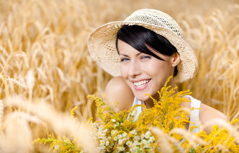 Pretty girl in straw hat against rye field