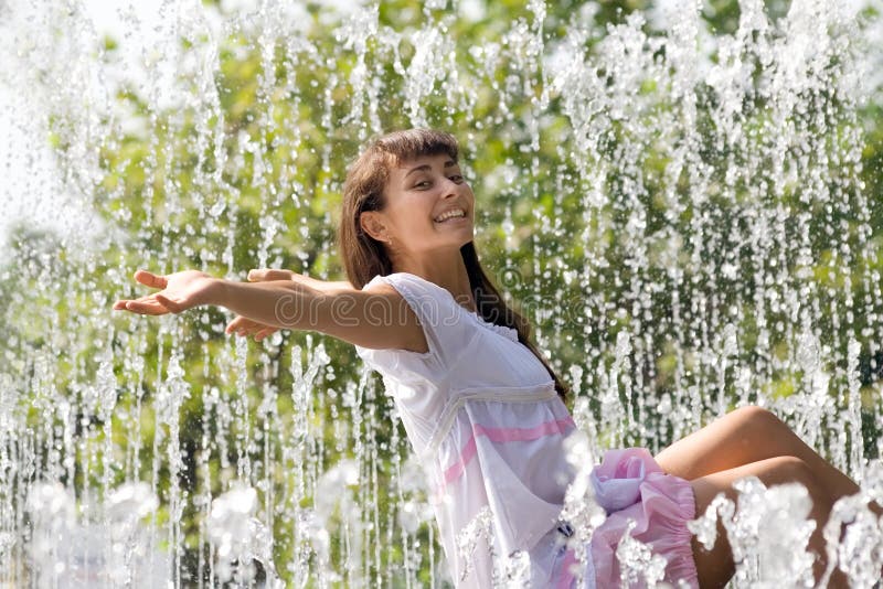 Pretty girl in the streams of the fountain