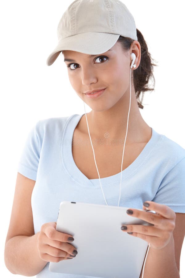 Pretty girl listening music, using tablet PC and earbuds, smiling. Pretty girl listening music, using tablet PC and earbuds, smiling.
