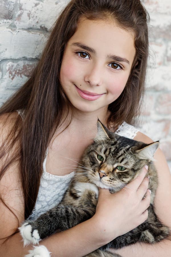 Pretty girl teenager 10-11 years holding a cat. 