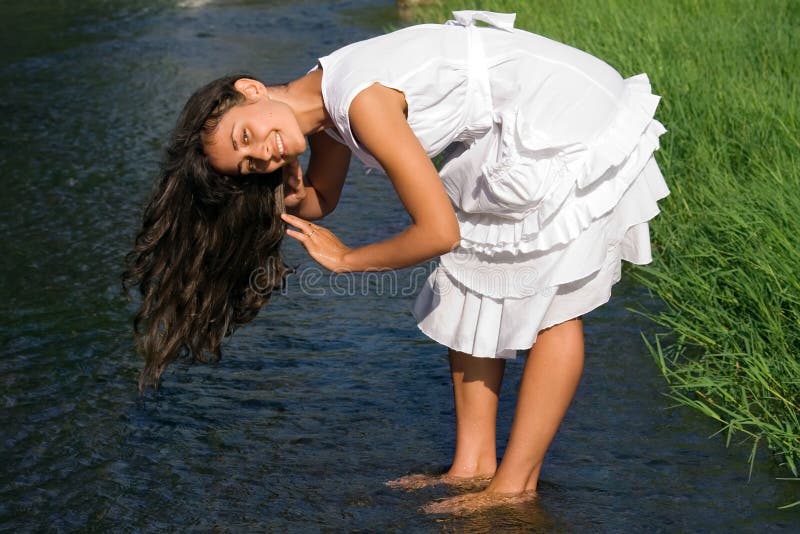 Pretty girl washing hair in the stream