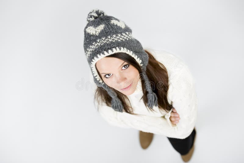 Pretty girl in winter clothes looking up with folded arms.