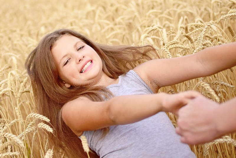 A pretty happy girl Laughing Holding the mother`s hands in golden rye field. Concept of purity, growth, happiness