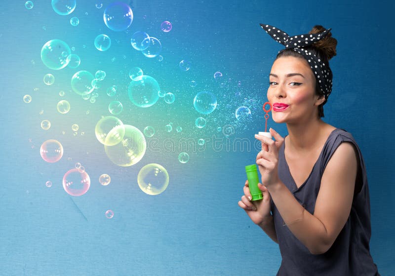 Pretty Lady Blowing Colorful Bubbles on Blue Background Stock Image