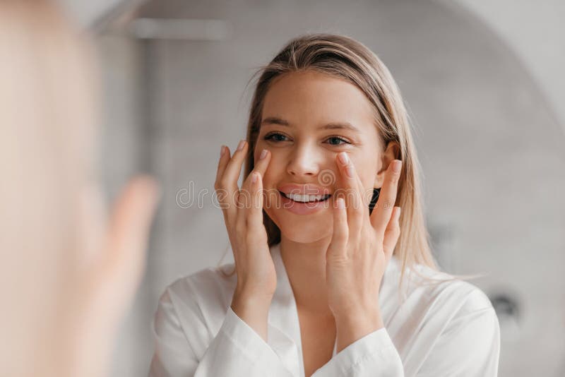 Pretty Lady Making Face Lifting Massage In Bathroom Looking At Mirror