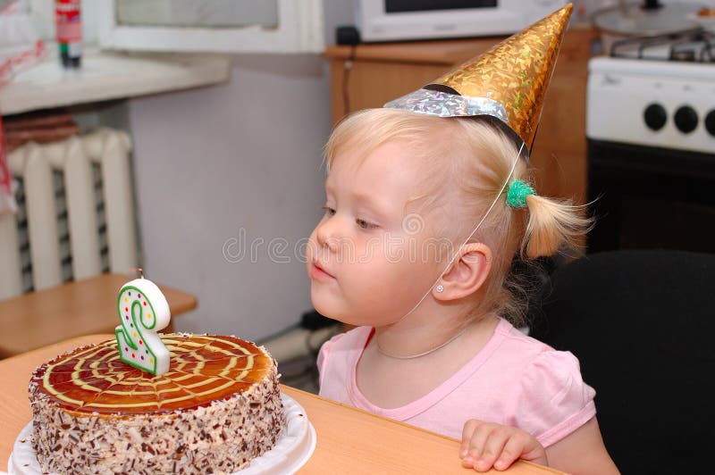 Pretty little girl in birthday cap and cake.