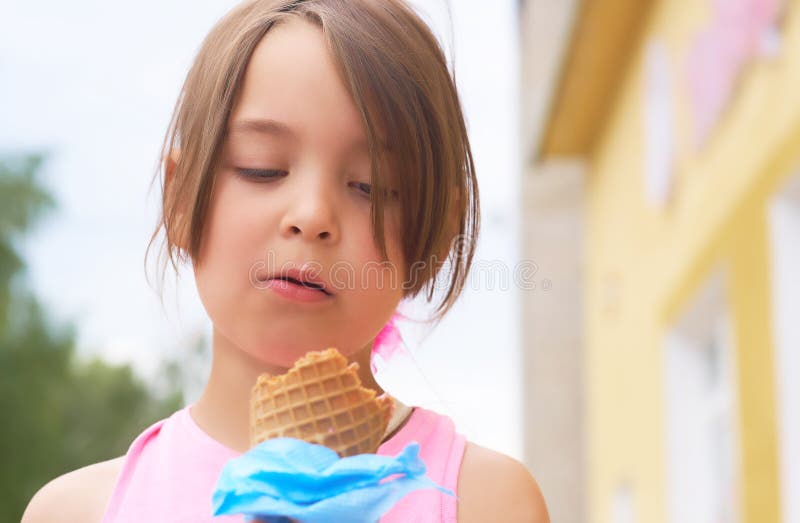Pretty little girl eating licking big ice cream in waffles cone happy laughing on nature background stock photo Pretty little girl eating licking big ice cream in waffles cone happy laughing on nature background stock photo