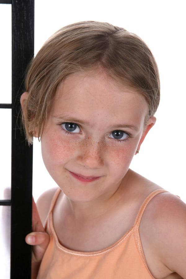 Pretty little girl with freckles on her nose, standing next to a screen.