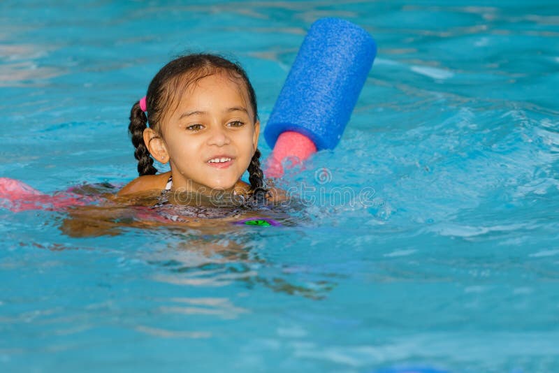 Pretty mixed race child swimming in pool royalty free stock photography