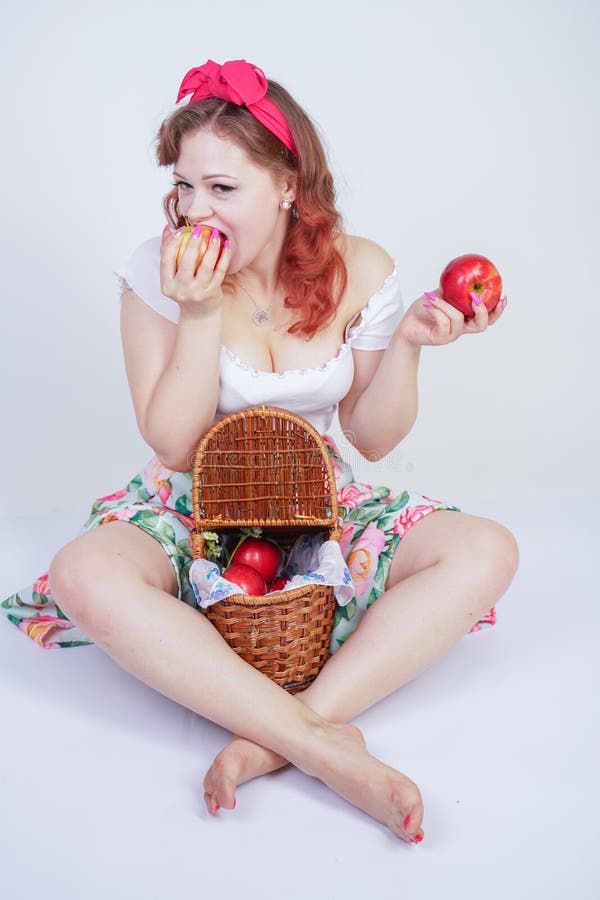 Pretty pin up caucasian young girl happy posing with red apples. cute vintage lady in retro dress having fun with fruits on white