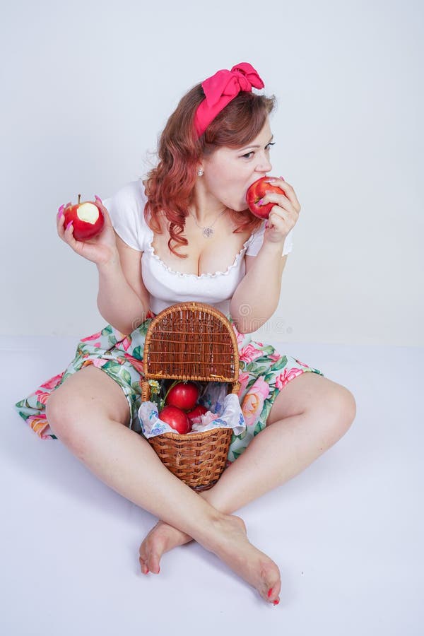 Pretty pin up caucasian young girl happy posing with red apples. cute vintage lady in retro dress having fun with fruits on white