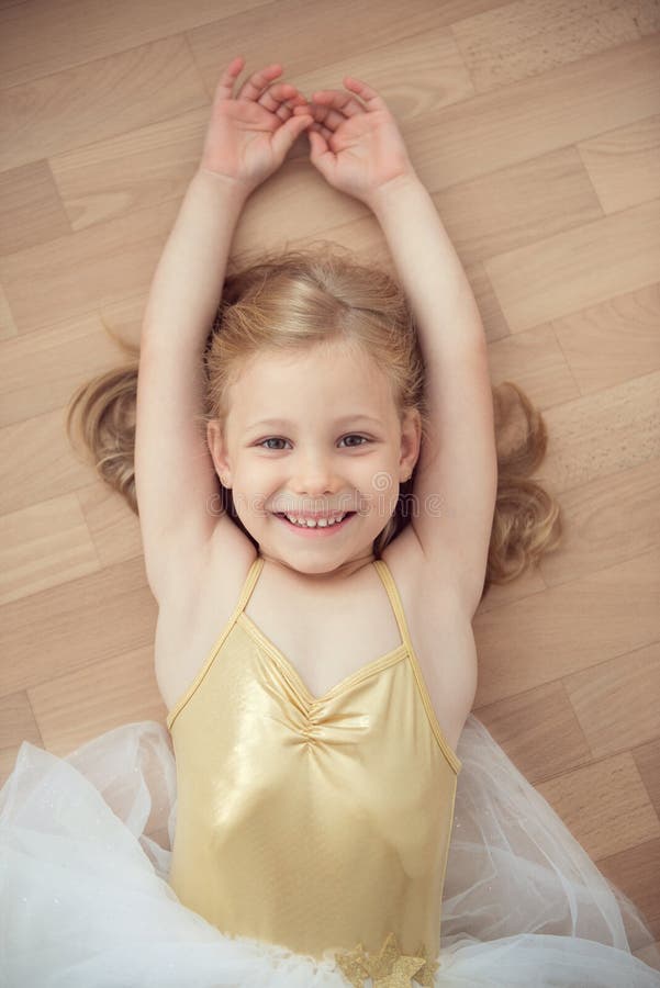 Pretty smiling ballet chilg girl in white tutu on floor stock image Pretty smiling ballet chilg girl in white tutu on floor stock image