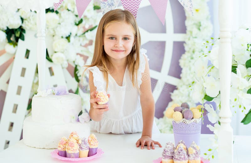 Pretty little blond girl standing in the beautiful decorated candy bar