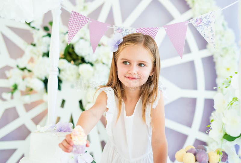 Pretty little blond girl standing in the beautiful decorated candy bar