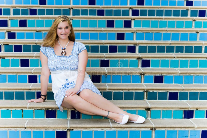 Pretty Teen Girl Sitting on Elegant Blue Steps royalty free stock photography