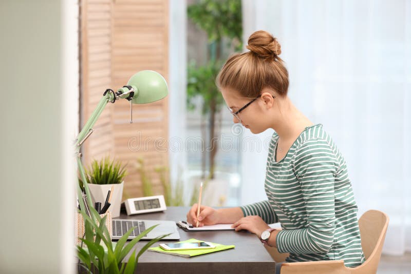 Pretty teenage girl doing homework at table stock image Pretty teenage girl doing homework at table stock image