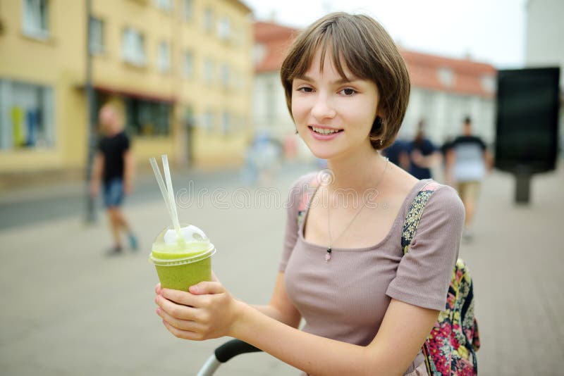 Pretty Teenage Girl Drinking Tasty Fresh Smoothie Outdoors On Warm 