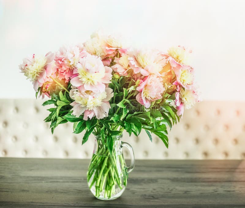 Pretty white pink peonies bouquet in glass vase on table, floral home interior design