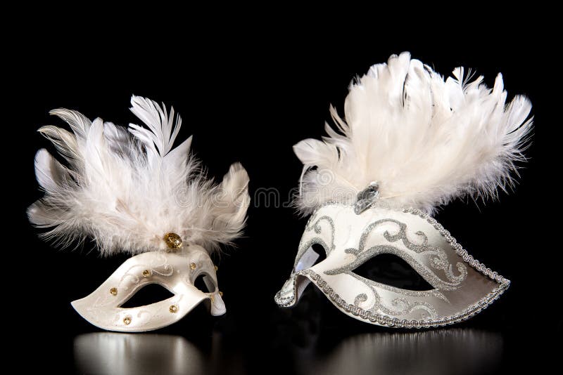 Pretty white venician golden carnival masks with feathers isolated on a mysterious black background. Pretty white venician golden carnival masks with feathers isolated on a mysterious black background