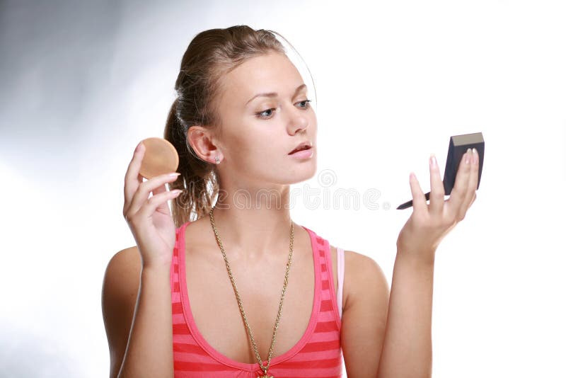 Pretty woman applying make-up with powder