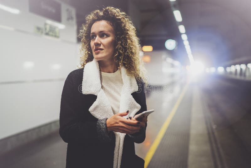 Pretty woman on commute transit using smartphone while standing in train station. Attractive girl happy using mobile stock photos Pretty woman on commute transit using smartphone while standing in train station. Attractive girl happy using mobile stock photos