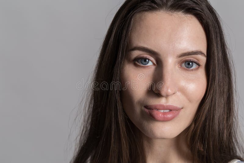 Pretty woman with fluffy hair, dressed casually against a gray studio wall