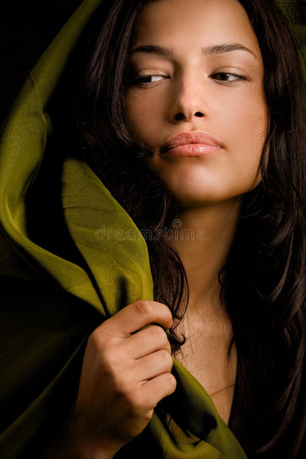 Un ritratto di una bella giovane donna con lunghi capelli scuri e una sciarpa verde drappeggiato sua testa e le spalle, come lei guarda alla sua destra.