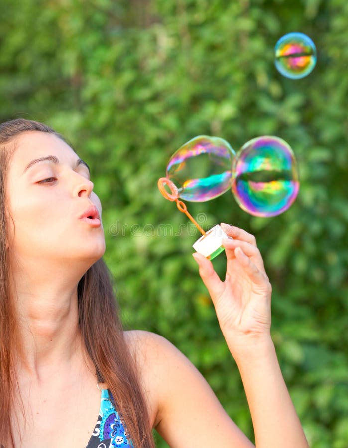 Pretty woman inflating soap bubbles.