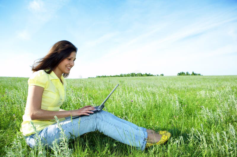 Pretty woman with laptop on the green grass