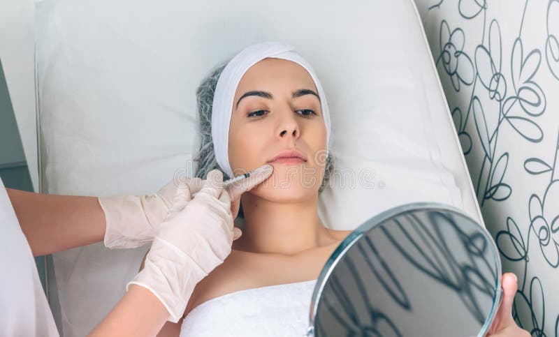 Pretty woman looking lips treatment in a mirror stock photography Pretty woman looking lips treatment in a mirror stock photography