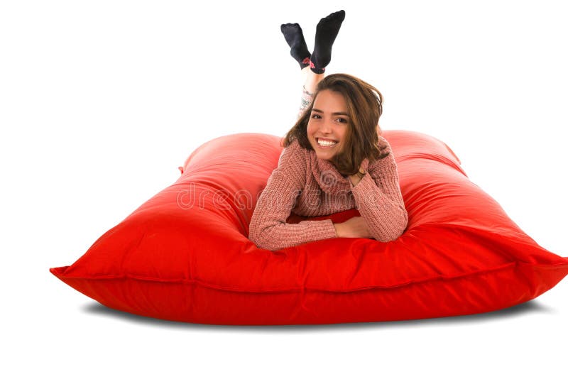 Pretty woman lying on red square shaped beanbag sofa isolated on