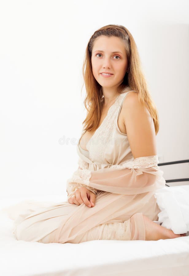 Pretty woman in nightrobe sitting in bed stock image