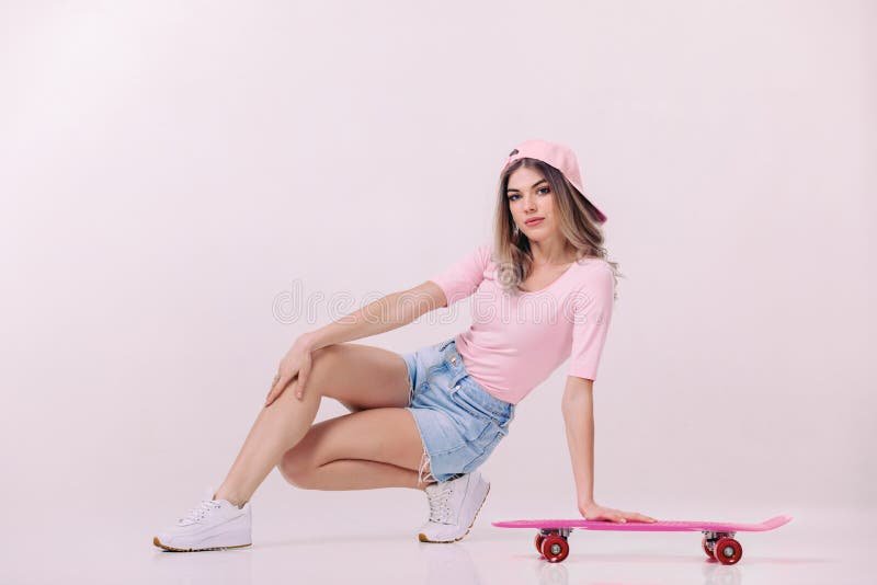 Beautiful woman in white t-shirt with pink skateboard.