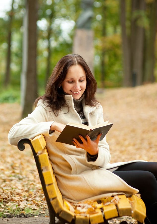 Pretty woman reading book on bench