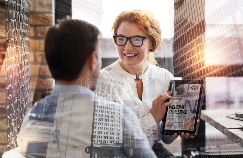 Pretty woman showing tablet with news article to her boss stock photo Pretty woman showing tablet with news article to her boss stock photo