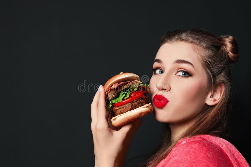 Pretty woman with tasty burger on black background