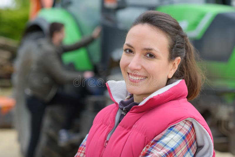 Pretty woman posing in front tractor