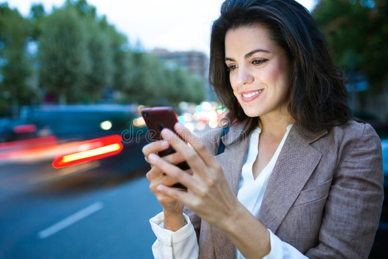 Pretty young businesswoman texting with her smartphone in the street near the highway. royalty free stock images Pretty young businesswoman texting with her smartphone in the street near the highway. royalty free stock images