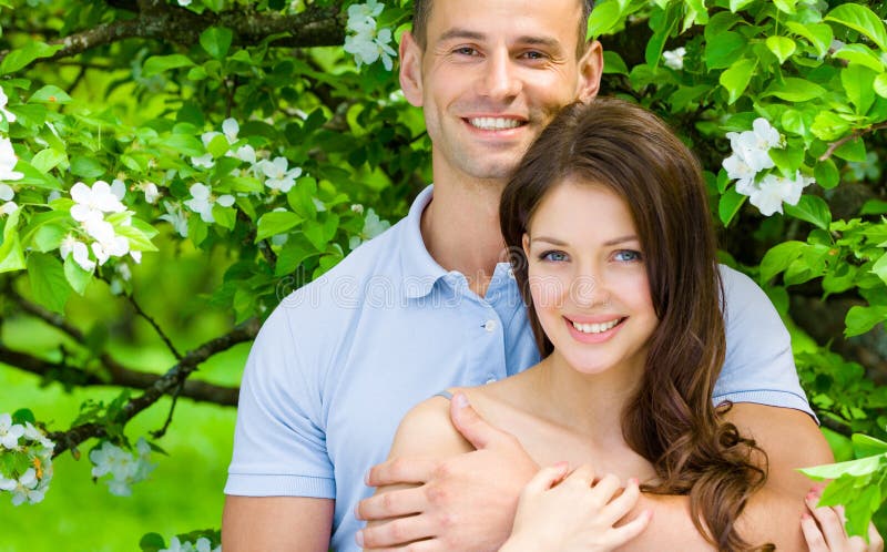Pretty young couple embracing near blossomed tree